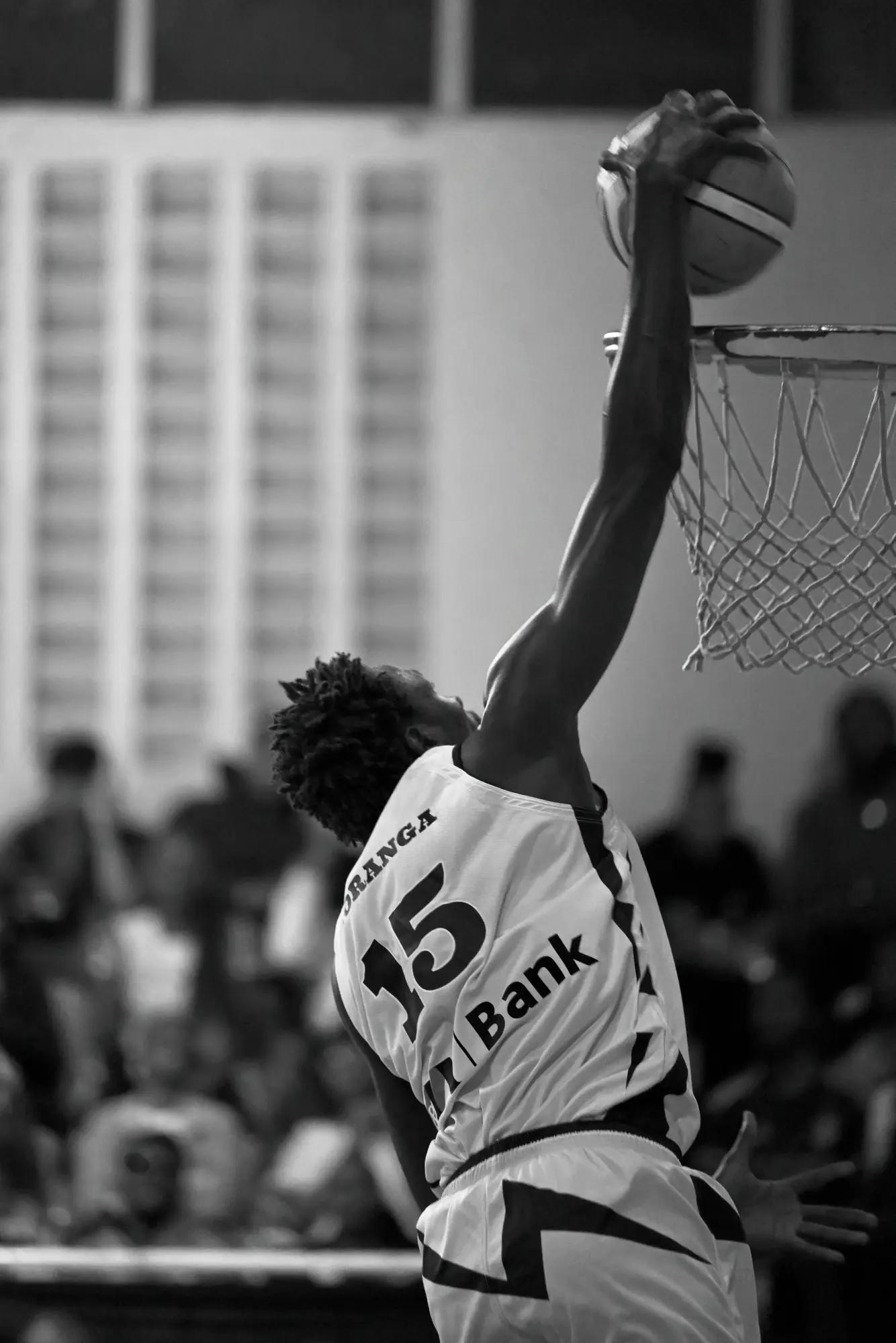 Nairobi City Thunder player stretching above the rim to lay the ball in, crowd dissolved behind
