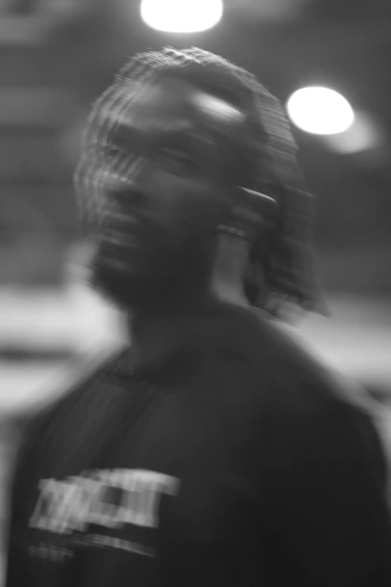 A player's head dissolves into vertical striations of motion between two blown arena lights