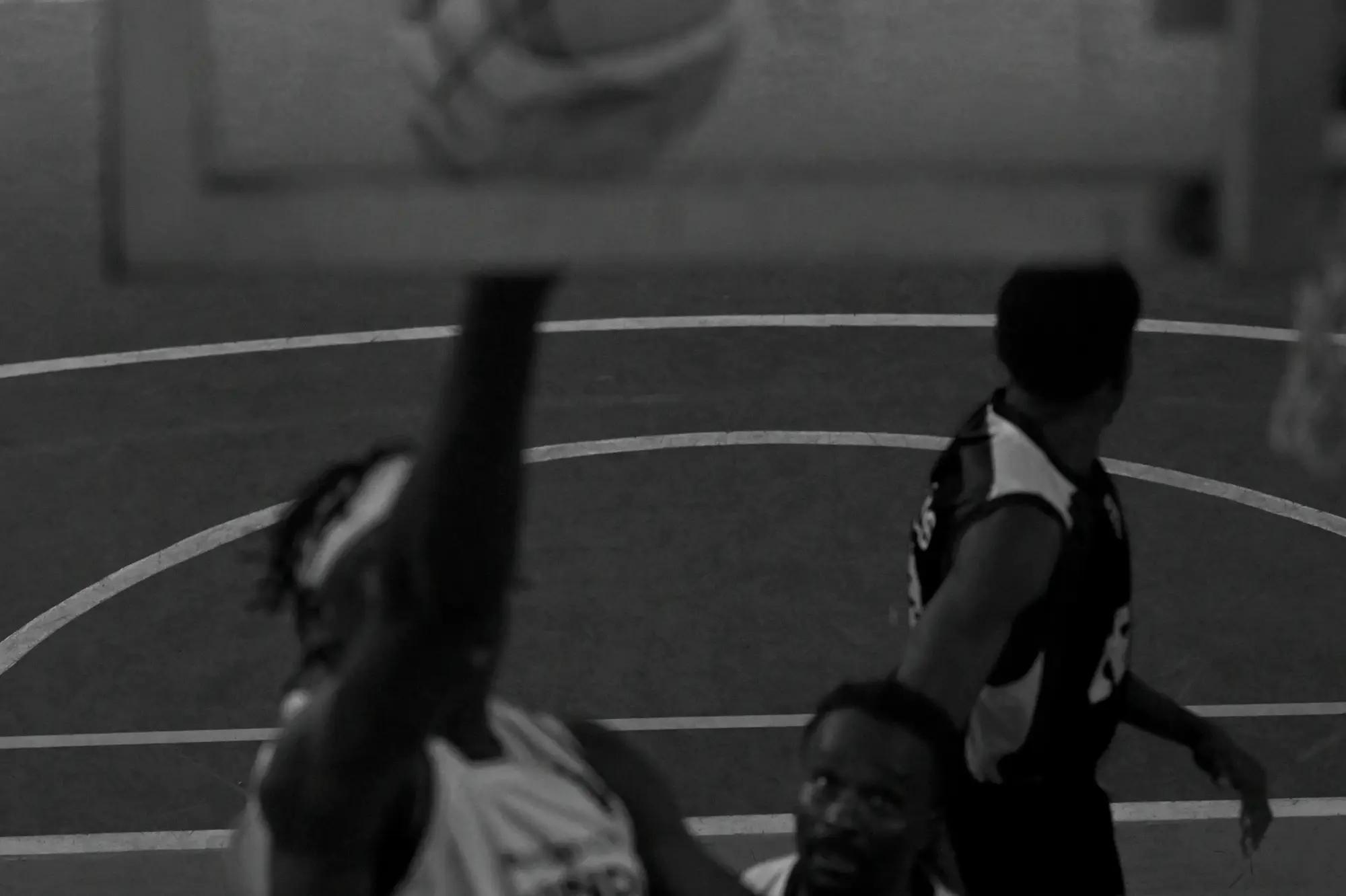 An out-of-focus body splits the court as an opponent walks off and a face looks up