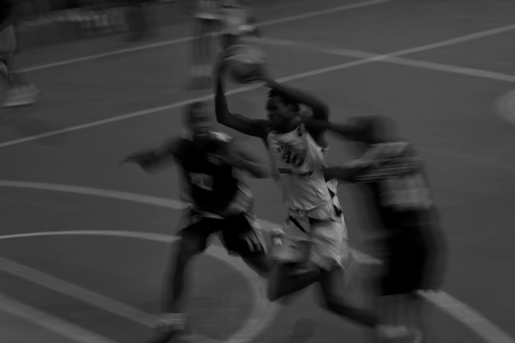 A Thunder guard swings the ball overhead and drives between two defenders, the whole frame dragged by a slow shutter